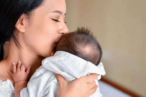 Madre abrazando a su bebé con síndrome de Menkes