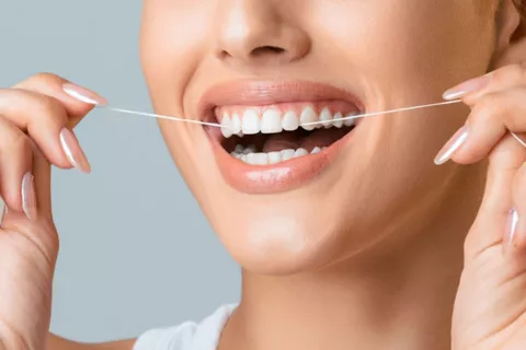 Chica usando un hilo dental después de comer