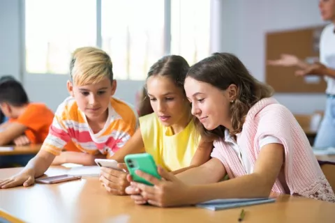 Grupo de escolares consultando whatsapp en sus teléfonos en el colegio
