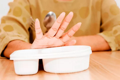 Mano de una señora de tercera edad apartando su comida