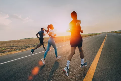 Tres corredores está corriendo en la carretera al aire libre al atardecer