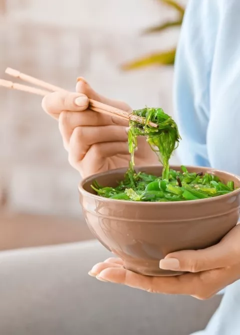 Mujer comiendo una ensalada de algas wakame