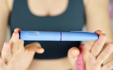 Mujer muestra una pluma de Ozempic y una cinta métrica Una mujer con ropa deportiva sujeta una pluma con semaglutida