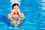 Una joven en la piscina se frota los ojos