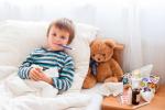 Niño con fiebre en la cama con un termómetro en la boca