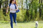Una mujer corre junto a su cachorro por un parque