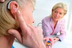 Una mujer mayor prueba un audífono en presencia de su médico