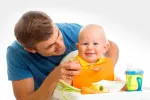 Alimentos ecológicos para tu bebé Un padre da a su hijo una papilla ecológica