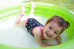 Peligros del calor para el bebé Niña pequeña refrescándose en la piscina