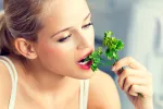 Beneficios del cilantro y contraindicaciones Una mujer muerde una rama de cilantro