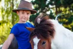 Beneficios de la equinoterapia Niño junto a un poni