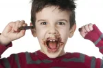 Causas del estreñimiento infantil Niño excitado comiendo mucho chocolate