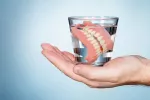 Prótesis o dentadura postiza conservada en un vaso de agua Consejos para cuidar la prótesis o dentadura postiza