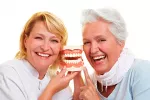 Qué prótesis dental elegir Pareja de mujeres maduras sosteniendo una prótesis dental