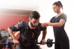 Tabla de ejercicios de gimnasia con electroestimulación Hombre con chaleco de electroestimulación realizando ejercicio
