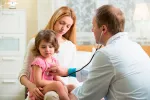 Ante la fiebre, ¿cuándo acudir al médico? Madre e hija con fiebre en el pediatra