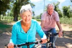 Una pareja de mayores monta en bicicleta por el campo
