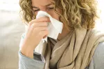 Síntomas de la gripe Mujer con gripe se suena la nariz