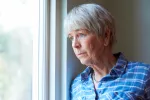 Sundowning: el síndrome del ocaso Mujer mayor deprimida mirando por la ventana
