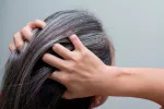 Canas, caspa, grasa y dieta Mujer mesándose las canas