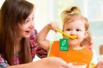 Crianza ecológica Una mama ofrece un alimento ecológico a su bebé