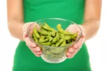 Mujer con un bol lleno de vainas de soja