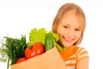La dieta de los niños, clave en su salud cardiovascular Una niña sostiene una bolsa con verduras