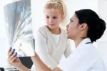 Alertan del abuso de pruebas radiológicas en los niños Una doctora le muestra una radiografía a una niña