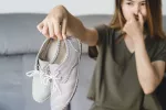 Mujer sujetando unas botas que desprenden mal olor