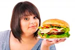 Una mujer obesa sostiene una enorme hamburguesa