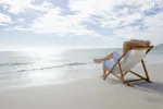 Tomar el sol y bañarse en el mar mejoran la psoriasis Hombre tomando el sol en la playa para mejorar su psoriasis