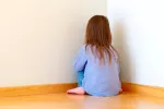 Asocian traumas infantiles y peor salud en la adultez Niña sentada de cara a la pared