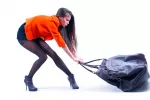 Advierten de los peligros de llevar un bolso pesado Una mujer se esfuerza en arrastrar un pesado bolso