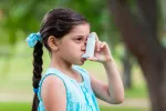 Bacterias intestinales previenen el asma infantil Niña utilizando un inhalador para el asma