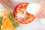 Un consumo adecuado de fibra puede ayudar a prevenir la obesidad Una mujer añade leche a un bol que contiene cereales y fruta