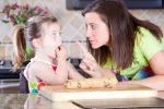 La razón por la que no debes comer la masa de las galletas cruda Madre regañando a su hija por comer masa de galletas cruda