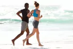 Correr descalzo reduce el riesgo de lesiones Una pareja corre descalza a la orilla del mar