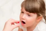 Niña pequeña tomando pastilla
