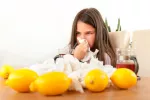Lo que necesita tu dieta para ayudarte a prevenir gripe y catarro Una joven se suena junto a una mesa con limones