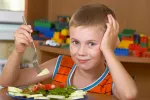 Niño con asma tomando un plato de dieta mediterránea