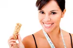 La ingesta de fibra reduce el riesgo de diabetes tipo 2 Una mujer sonríe mientras muestra una barrita de cereales
