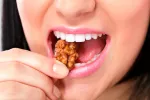 Las nueces pueden ralentizar el cáncer de colon Mujer comiendo una nuez.