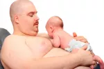 Los padres primerizos suelen engordar Un padre obeso sostiene a su bebé