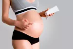 Una mujer embarazada se aplica una crema sobre la barriga