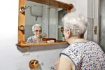 Alrededor del 80% de los enfermos de Parkinson sufre problemas orales Mujer con Parkinson lavándose los dientes