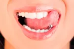 Los piercings en la lengua pueden provocar daños en dientes y encías Mujer con un piercing en la lengua