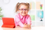 Los problemas visuales pueden derivar en fracaso escolar Niña pequeña con gafas sonríe a la cámara