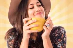 Una joven sostiene una taza de té en las manos con gesto satisfecho