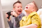 Una hora de videojuegos por semana mejora habilidades en niños Dos niños ríen a carcajadas con un videojuego