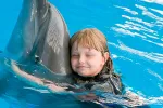 Una niña abraza a un delfín en el agua